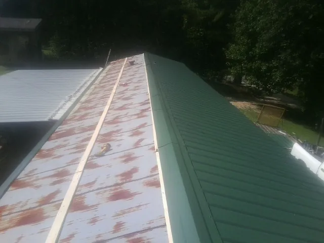 Old rusted panels beside newly installed green metal roofing — Wind Damage Roof Repair by Roofing Brothers in Bliss