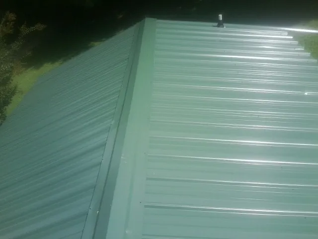 New green metal panels meeting at the ridge of a roof — Flat Roof Repair work by our crew in Bliss