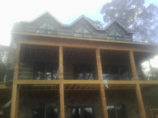 Dormers and porch framing on a large log home under construction — Roof Coating work by our crew in Bliss