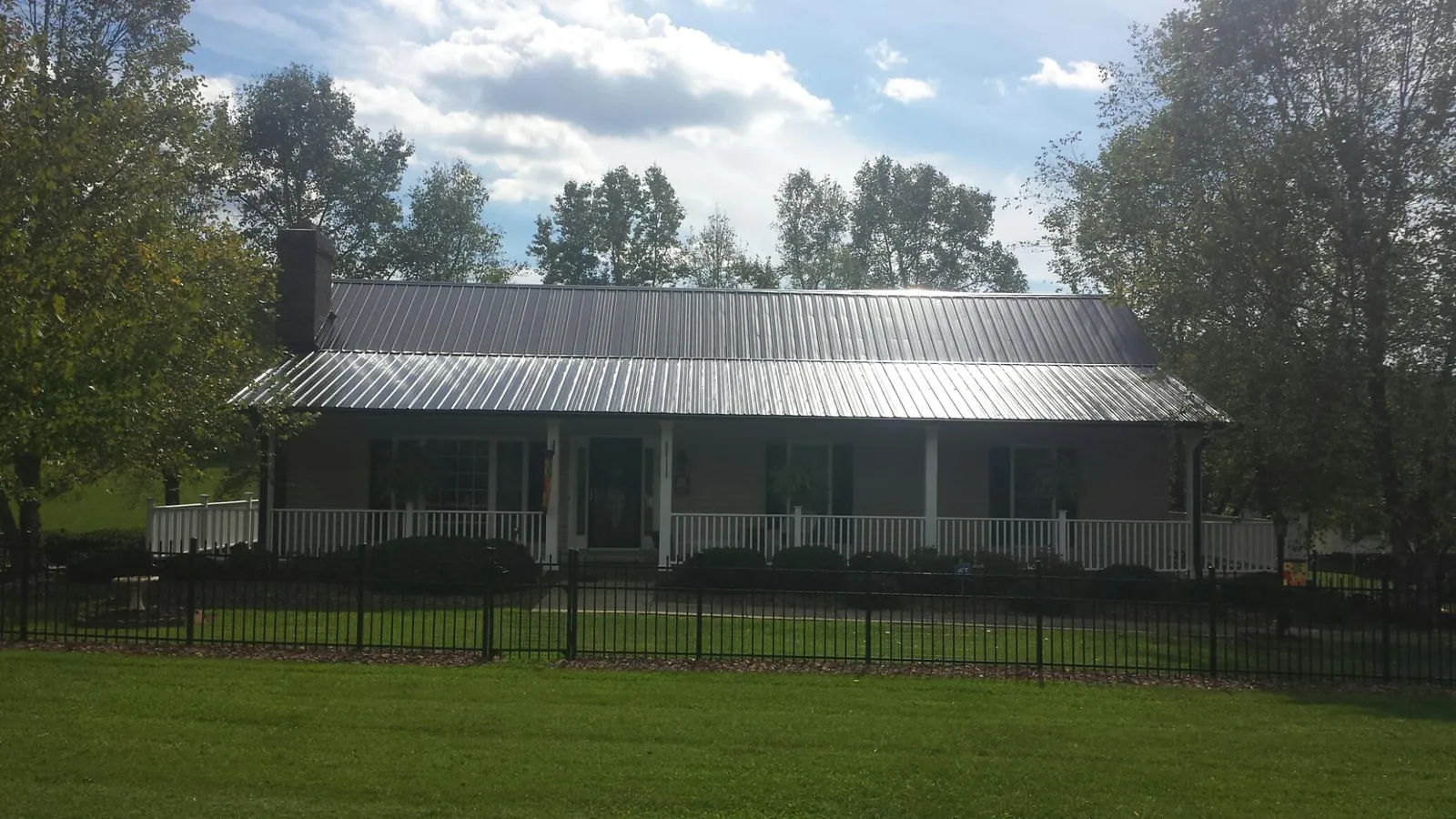 Gray metal roof on a brick ranch with a full width front porch — Gutter Guard Installation work by our crew in Bliss